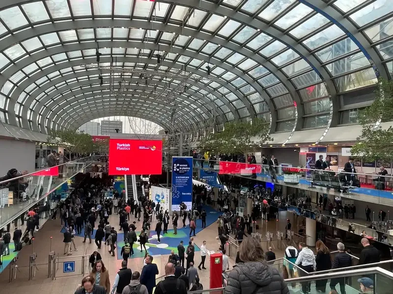 Entrada principal e área de exposição da K-Messe 2025 em Düsseldorf, com visitantes, estandes e estruturas do evento.