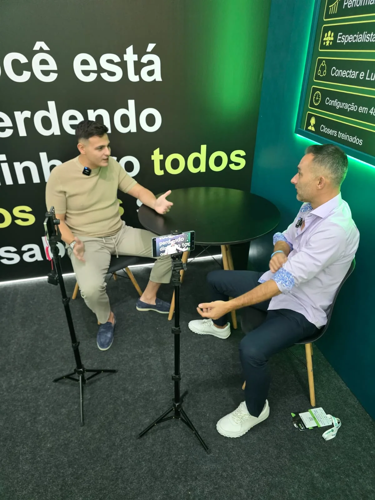 Man in a blue blazer being interviewed on a phone camera at the iSellForYou stand, Afiliados Brasil expo