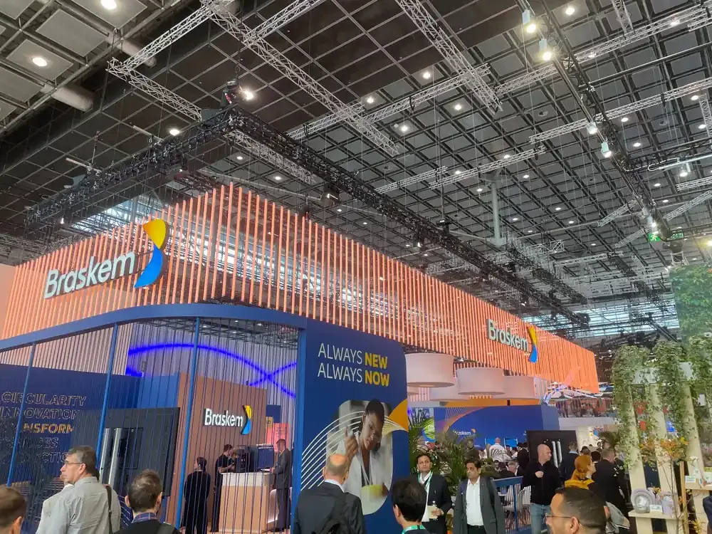 Estande da Braskem na K 2025 em Düsseldorf com fachada laranja ripada e visitantes circulando
