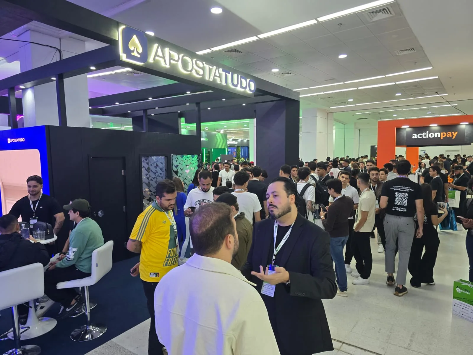 Crowded Afiliados Brasil expo hall with the ApostaTudo and actionpay booths in the background, São Paulo