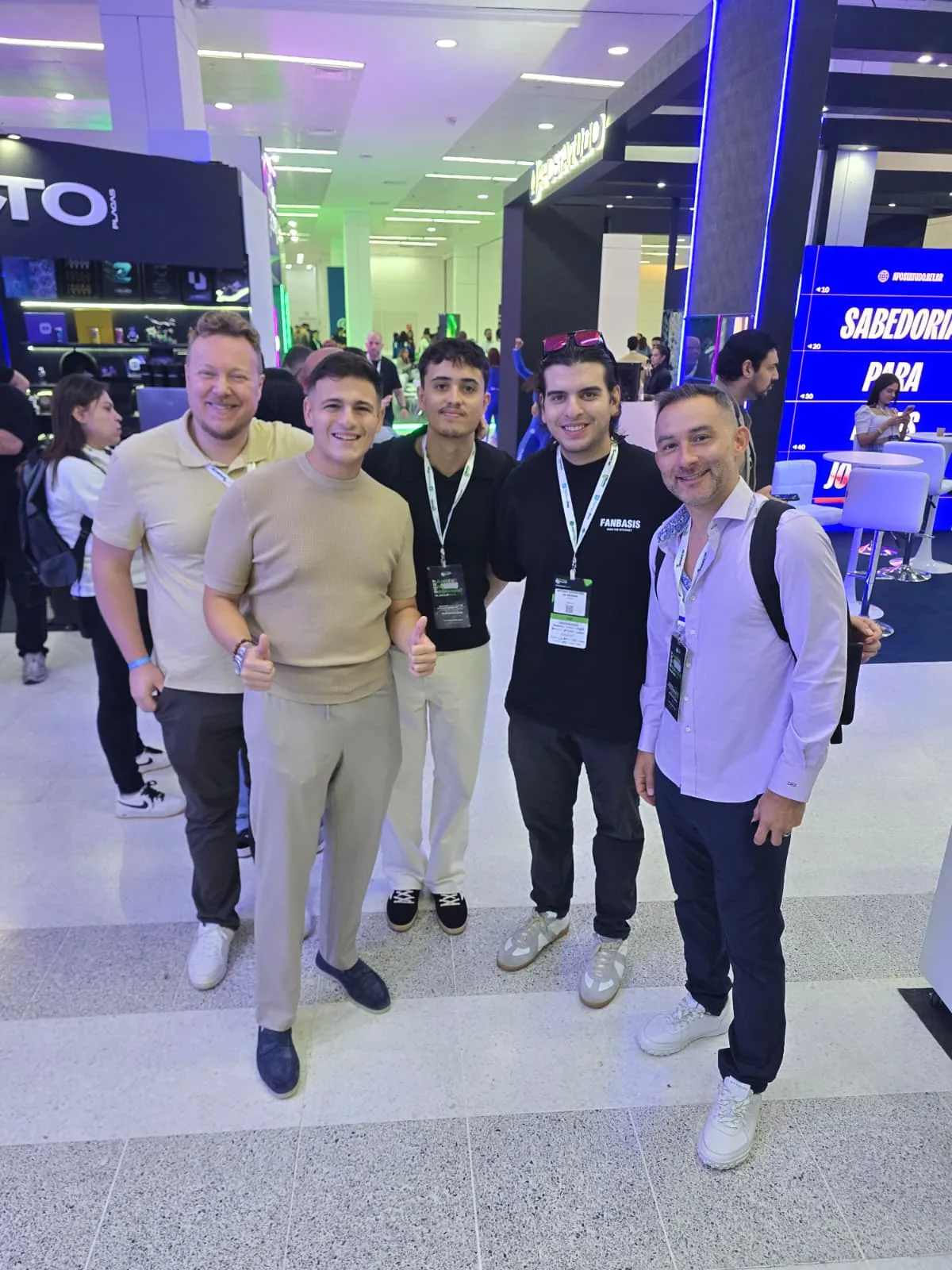 Five men with badges smiling, some giving a thumbs up, in the Afiliados Brasil expo hall