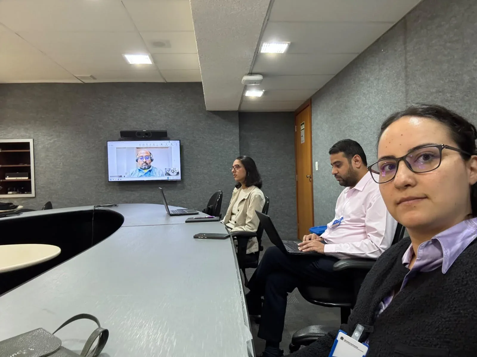 Meeting participants in Brasília following a remote interpreter shown on the room's TV via video call