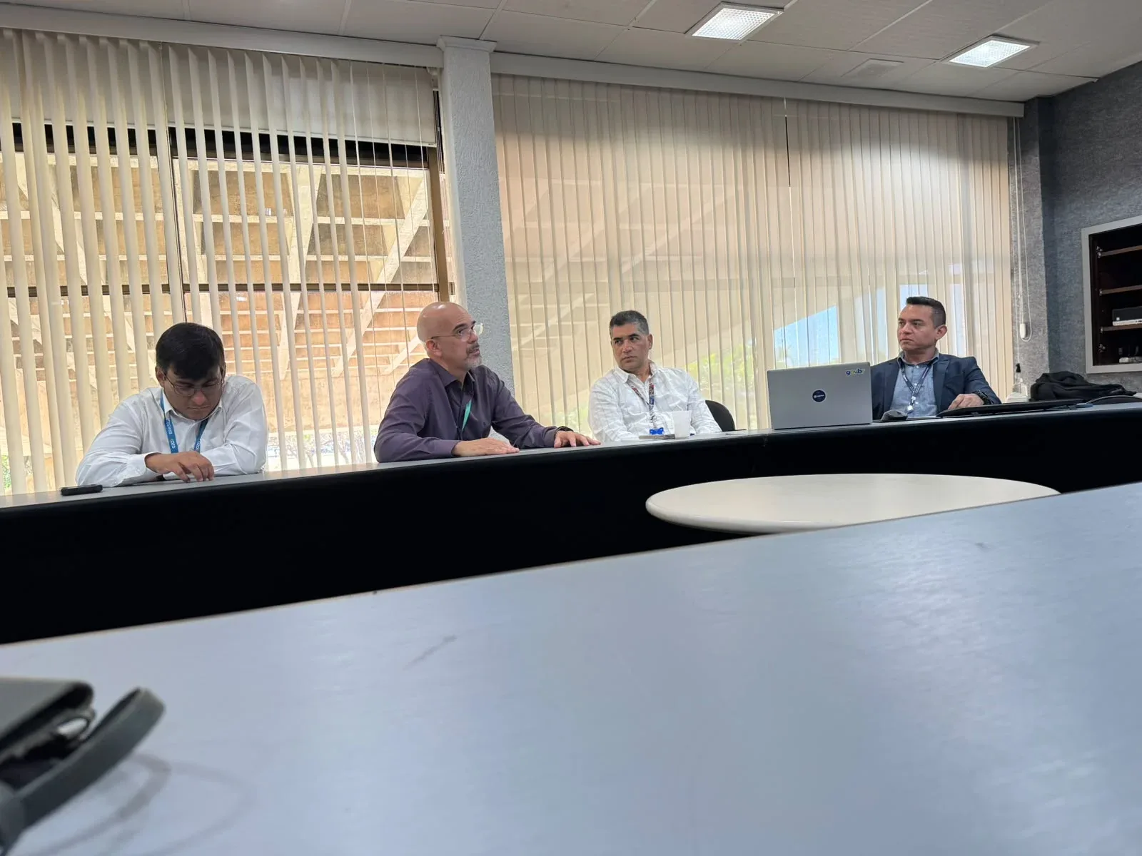 Four participants at an institutional meeting table in Brasília with Portuguese–English interpretation