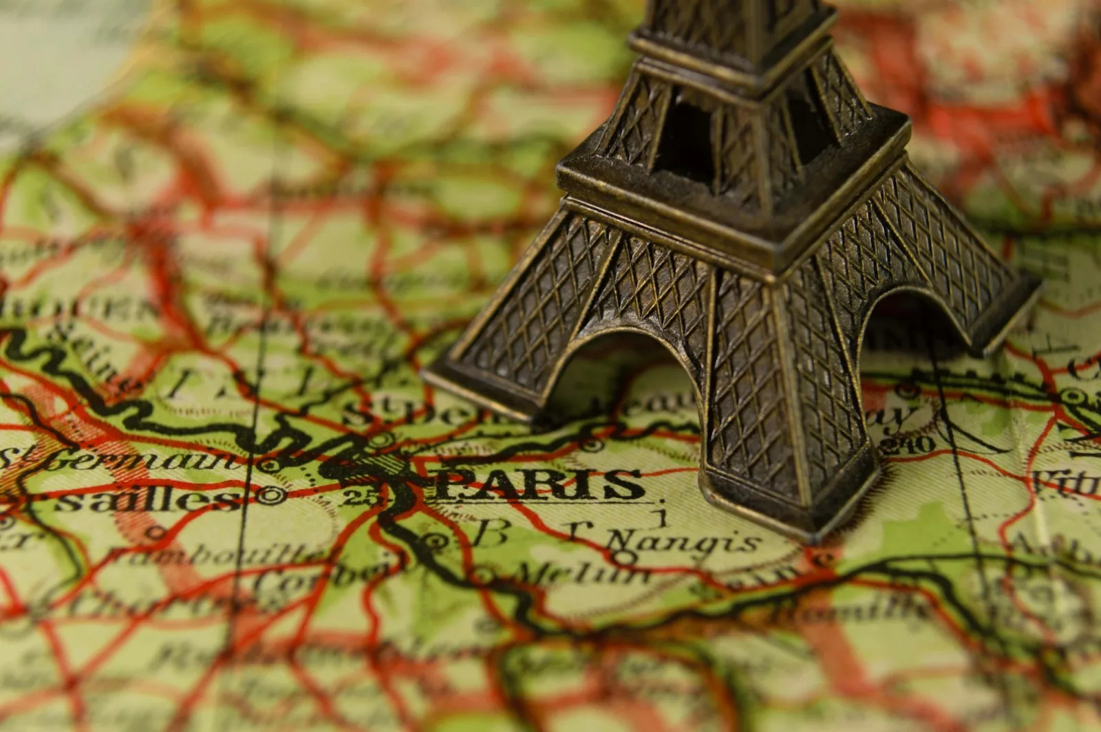 Miniatura da Torre Eiffel sobre um mapa antigo da França com Paris em destaque