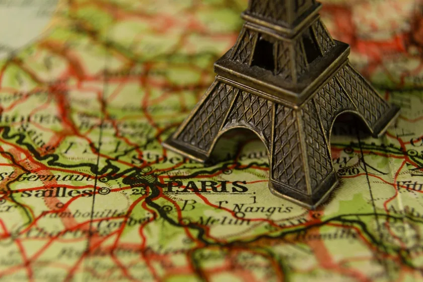 Miniatura da Torre Eiffel sobre um mapa antigo da França com Paris em destaque
